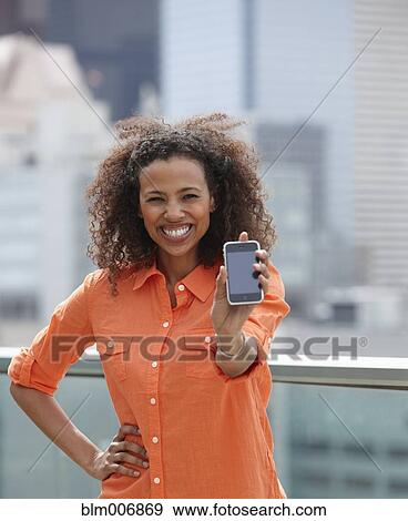 Stock Photo - Black woman holding out cell phone. Fotosearch