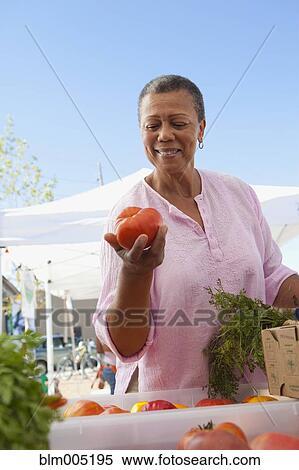 Stock Photography - Black woman holding tomato. Fotosearch