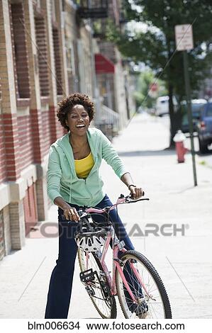 Picture - Black woman on bicycle in city. Fotosearch