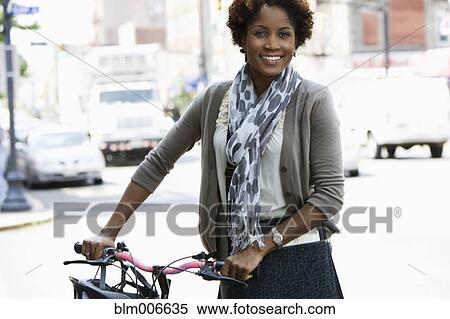 Stock Photography - Black woman on bicycle in city. Fotosearch