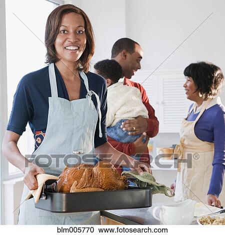 Stock Image - Black woman preparing Thanksgiving dinner. Fotosearch