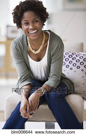Picture - Black woman sitting in living room. Fotosearch