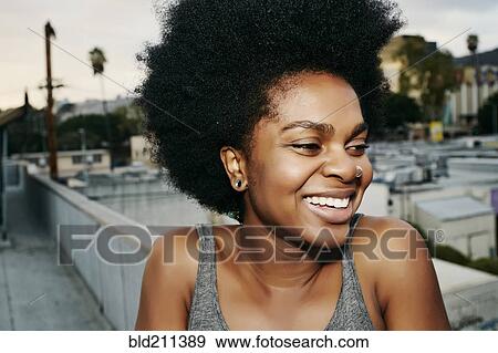 Stock Photo - Black woman smiling on urban rooftop. Fotosearch