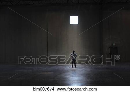 Picture - Black woman standing in empty warehouse. Fotosearch