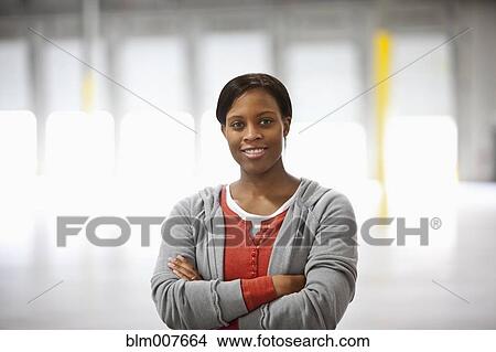 Picture - Black woman standing in warehouse. Fotosearch