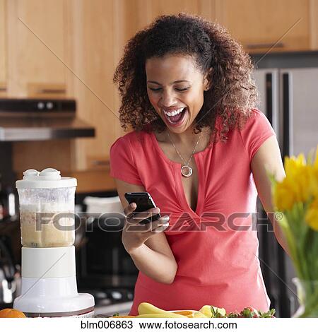 Black woman text messaging on cell phone in kitchen View Large Photo Image Stock Image - Black woman text messaging on cell phone in kitchen. Fotosearch