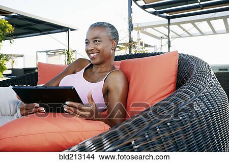 Picture - Black woman using digital tablet on urban rooftop. Fotosearch