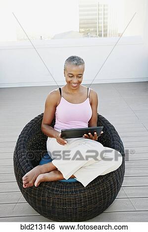 Stock Photograph - Black woman using digital tablet on urban rooftop. Fotosearch