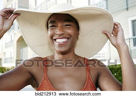 Stock Image - Black woman wearing sun hat outdoors. Fotosearch