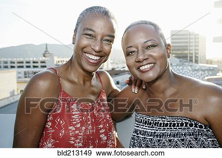 Black women smiling together on urban rooftop View Large Photo Image Stock Photo - Black women smiling together on urban rooftop. Fotosearch