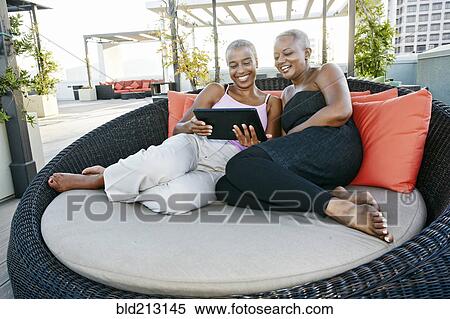 Stock Photography - Black women using digital tablet together on urban rooftop. Fotosearch