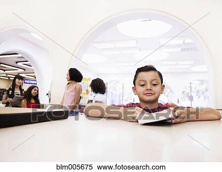 Stock Photography - Boy checking out books from library. Fotosearch