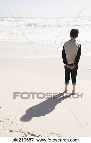 Boy standing on sunny beach View Large Photo Image Stock Photo - Boy standing on sunny beach. Fotosearch