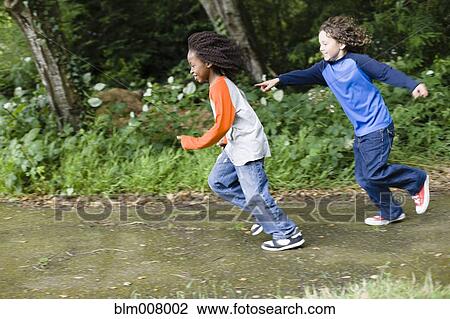 Stock Image - Boys playing tag in the park. Fotosearch