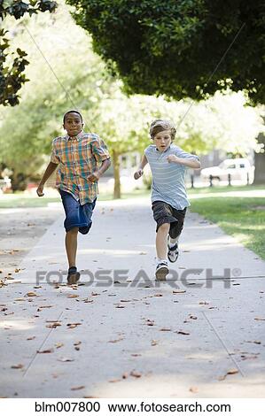 Stock Image - Boys running on sidewalk. Fotosearch
