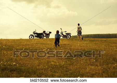 Boys running to motorcycles in rural landscape View Large Photo Image Stock Image - Boys running to motorcycles in rural landscape. Fotosearch