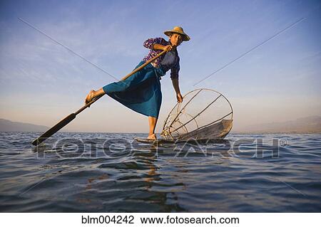 Burmese woman using legs to row on lake View Large Photo Image Stock Image - Burmese woman using legs to row on lake. Fotosearch