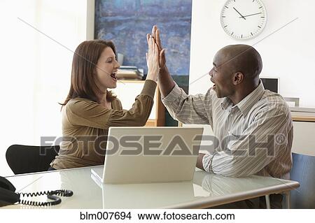 Business people high-fiving in office View Large Photo Image Picture - Business people high-fiving in office. Fotosearch