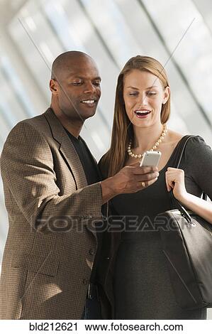 Business people using cell phone in lobby View Large Photo Image Stock Image - Business people using cell phone in lobby. Fotosearch