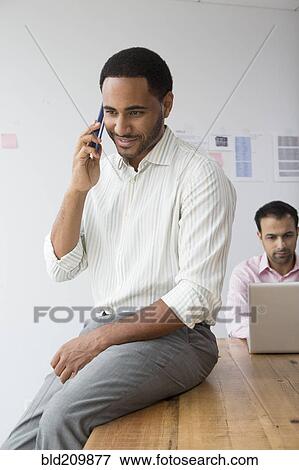 Businessman talking on telephone in office View Large Photo Image Stock Photo - Businessman talking on telephone in office. Fotosearch