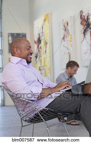 Businessman working in art gallery on laptop View Large Photo Image Stock Photo - Businessman working in art gallery on laptop. Fotosearch