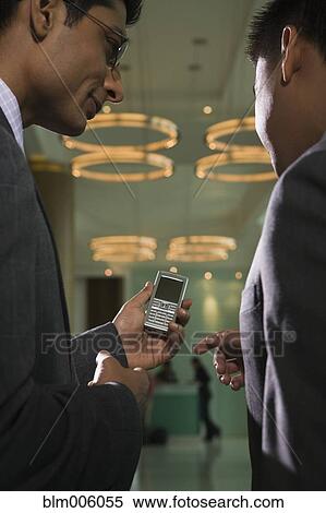 Stock Photography - Businessmen looking at cell phone. Fotosearch