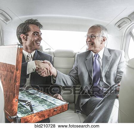 Stock Photo - Businessmen shaking hands in backseat of car. Fotosearch
