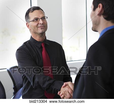 Picture - Businessmen shaking hands in office. Fotosearch