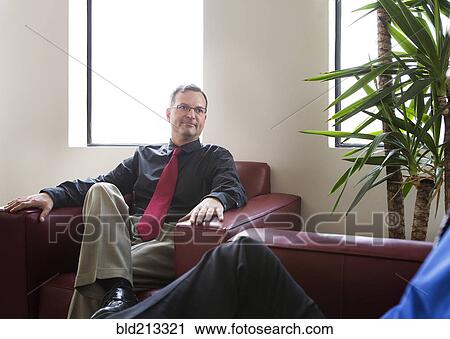 Stock Image - Businessmen talking in armchairs in office. Fotosearch