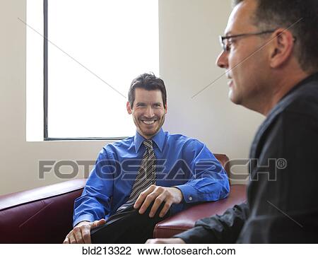 Stock Image - Businessmen talking in armchairs in office. Fotosearch