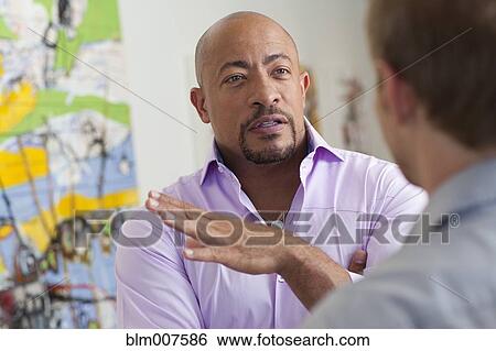 Stock Photograph - Businessmen talking in art gallery. Fotosearch
