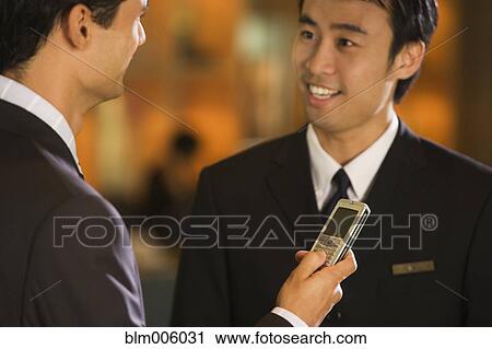 Stock Image - Businessmen talking, one with cell phone. Fotosearch
