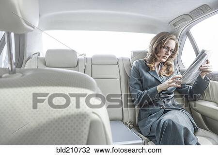 Businesswoman reading newspaper in car View Large Photo Image Stock Image - Businesswoman reading newspaper in car. Fotosearch