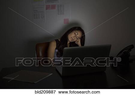 Stock Photo - Businesswoman sleeping at desk at night. Fotosearch