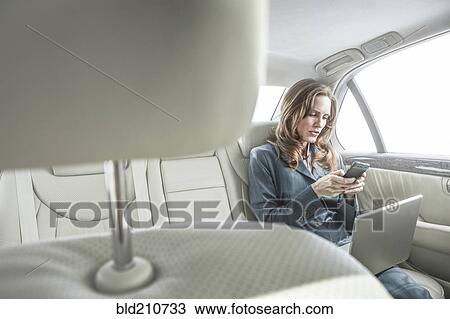 Stock Image - Businesswoman working in backseat of car. Fotosearch