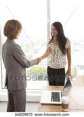 Businesswomen shaking hands in office View Large Photo Image Stock Image - Businesswomen shaking hands in office. Fotosearch