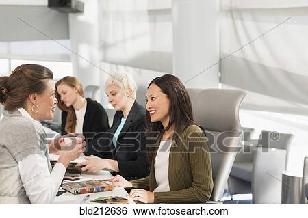Stock Photograph - Businesswomen talking in meeting. Fotosearch