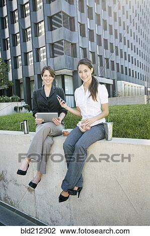 Stock Image - Businesswomen using tablet computer in city. Fotosearch