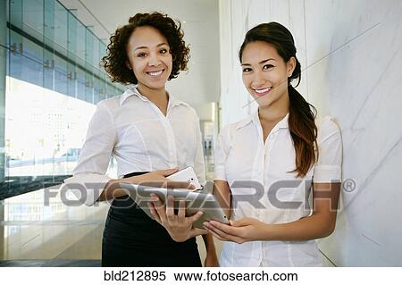 Businesswomen using tablet computer in lobby View Large Photo Image Stock Photography - Businesswomen using tablet computer in lobby. Fotosearch