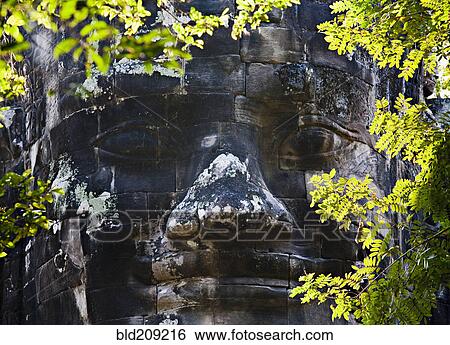Stock Photograph - Carved stone face, Angkor, Cambodia. Fotosearch