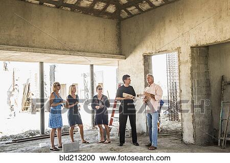 Stock Image - Caucasian architects talking at construction site. Fotosearch