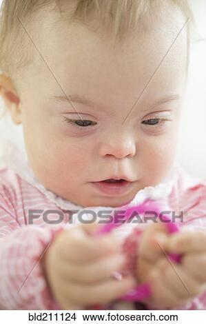 Picture - Caucasian baby girl with Down Syndrome playing with ring. Fotosearch