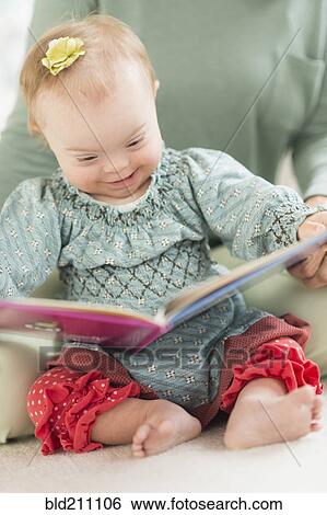 Stock Photograph - Caucasian baby girl with Down Syndrome reading. Fotosearch