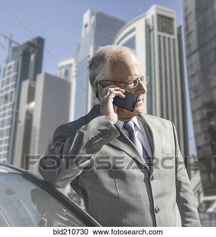 Stock Image - Caucasian businessman on cell phone by city skyline. Fotosearch