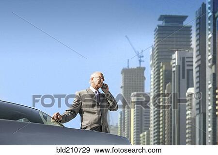 Stock Photo - Caucasian businessman on cell phone by city skyline. Fotosearch