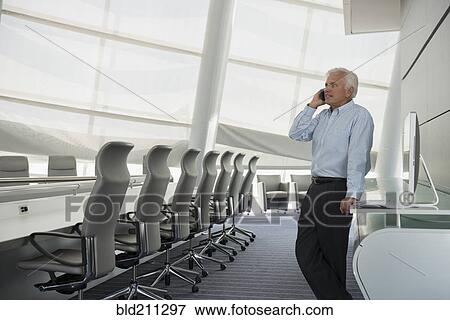 Stock Photo - Caucasian businessman on cell phone in conference room. Fotosearch