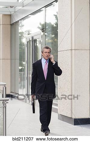 Stock Photo - Caucasian businessman on cell phone outdoors. Fotosearch