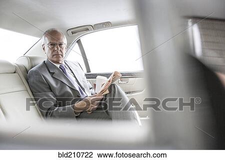 Caucasian businessman reading newspaper in car View Large Photo Image Stock Image - Caucasian businessman reading newspaper in car. Fotosearch
