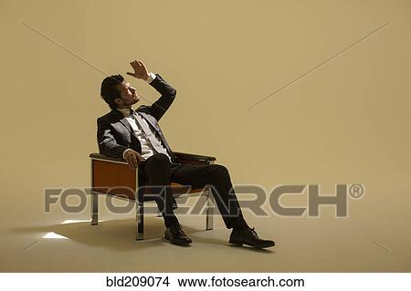 Picture - Caucasian businessman sitting under spotlight. Fotosearch