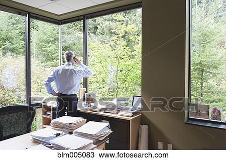 Caucasian businessman talking on cell phone in office View Large Photo Image Stock Image - Caucasian businessman talking on cell phone in office. Fotosearch